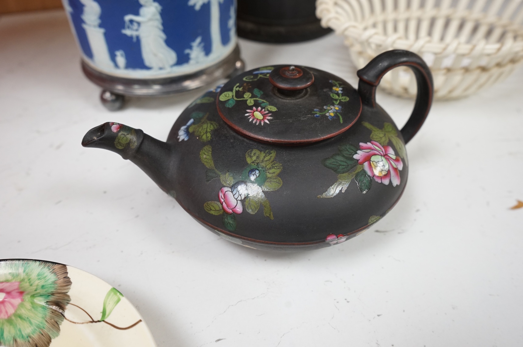 A collection of Wedgwood comprising basalt and jasper biscuit barrels, an enamelled basalt teapot, and a cover and creamware basket, largest 26cm high (4)